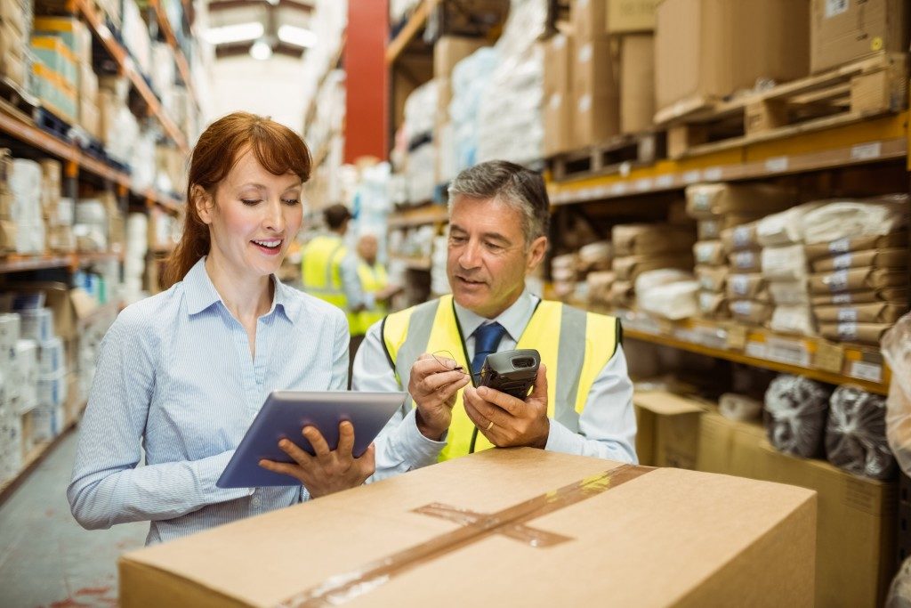 woman holding laptop man holding a scanner in warehouse