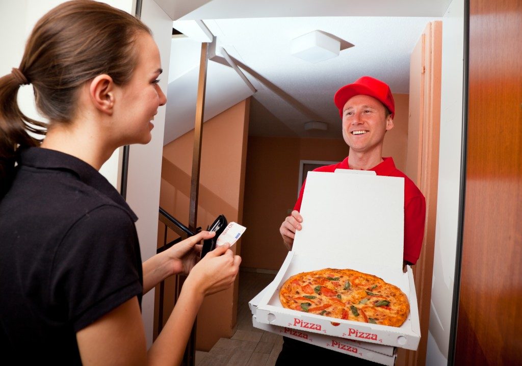 Woman receiving her pizza from delivery man