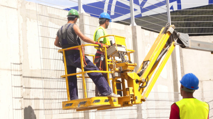 Hydraulic mobile construction platform elevated towards a blue sky with construction workers